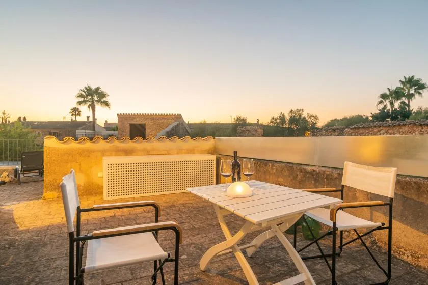 Una terraza en la azotea con una mesa y sillas y vistas al paisaje circundante.
