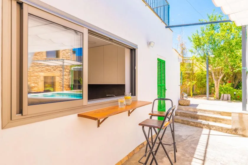 Un patio luminoso con una barra, asientos al aire libre y un jardín.