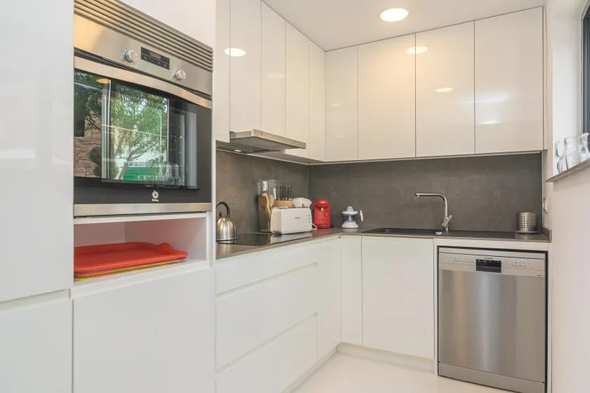 Una cocina moderna con gabinetes blancos, un horno empotrado y un fregadero.