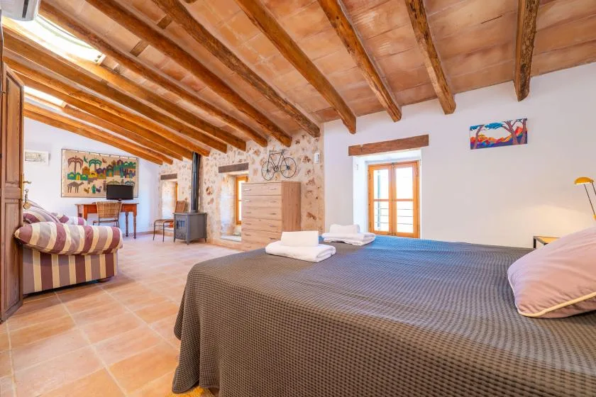 Un dormitorio con una cama grande, vigas de madera expuestas y una zona de estar.