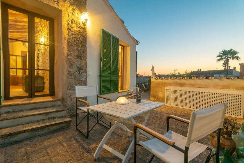 Una terraza exterior pavimentada con piedra, mesa y asientos al atardecer.