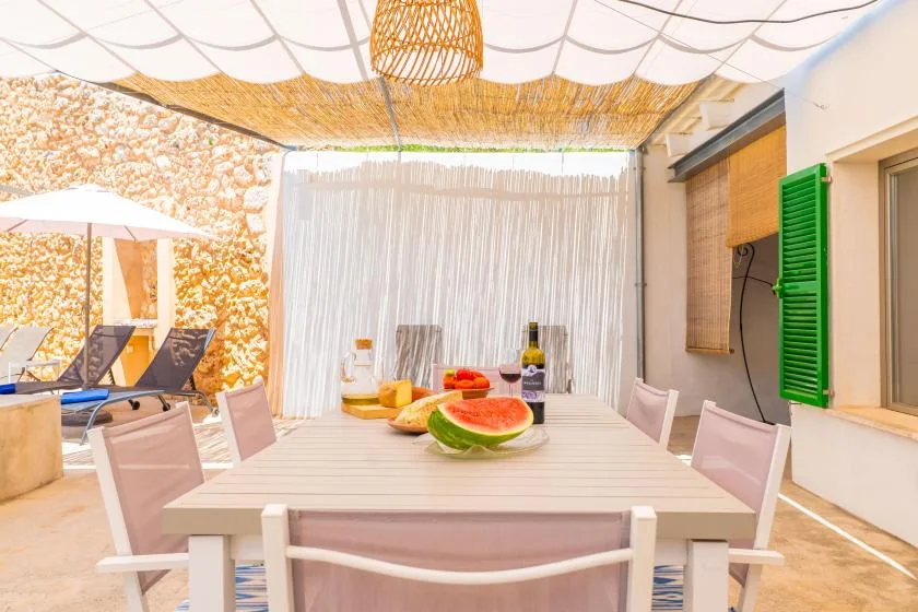 Una zona de comedor al aire libre con una mesa bajo un toldo tejido.
