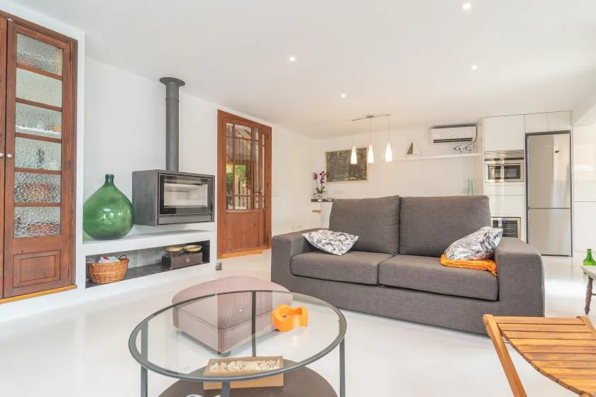 Una sala luminosa con asientos grises, una mesa de centro de vidrio y una chimenea.