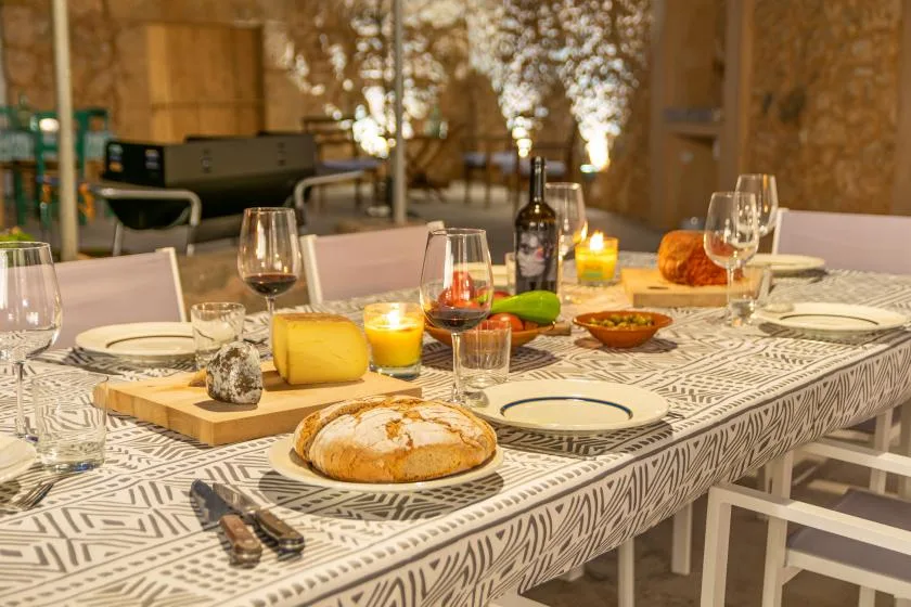 Una mesa de comedor está puesta con platos, copas, pan y velas.