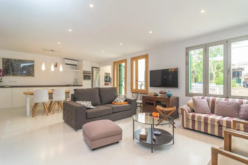 Una sala luminosa con sofás, una mesa de centro y una cocina abierta.