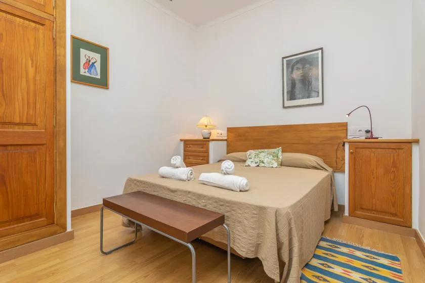Un dormitorio con una cama doble, mesillas de noche y un banco pequeño.