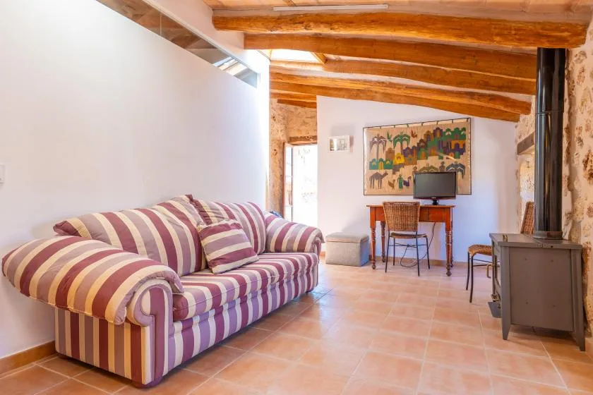 Una sala de estar con un sofá a rayas, una mesa pequeña y vigas de madera vistas.