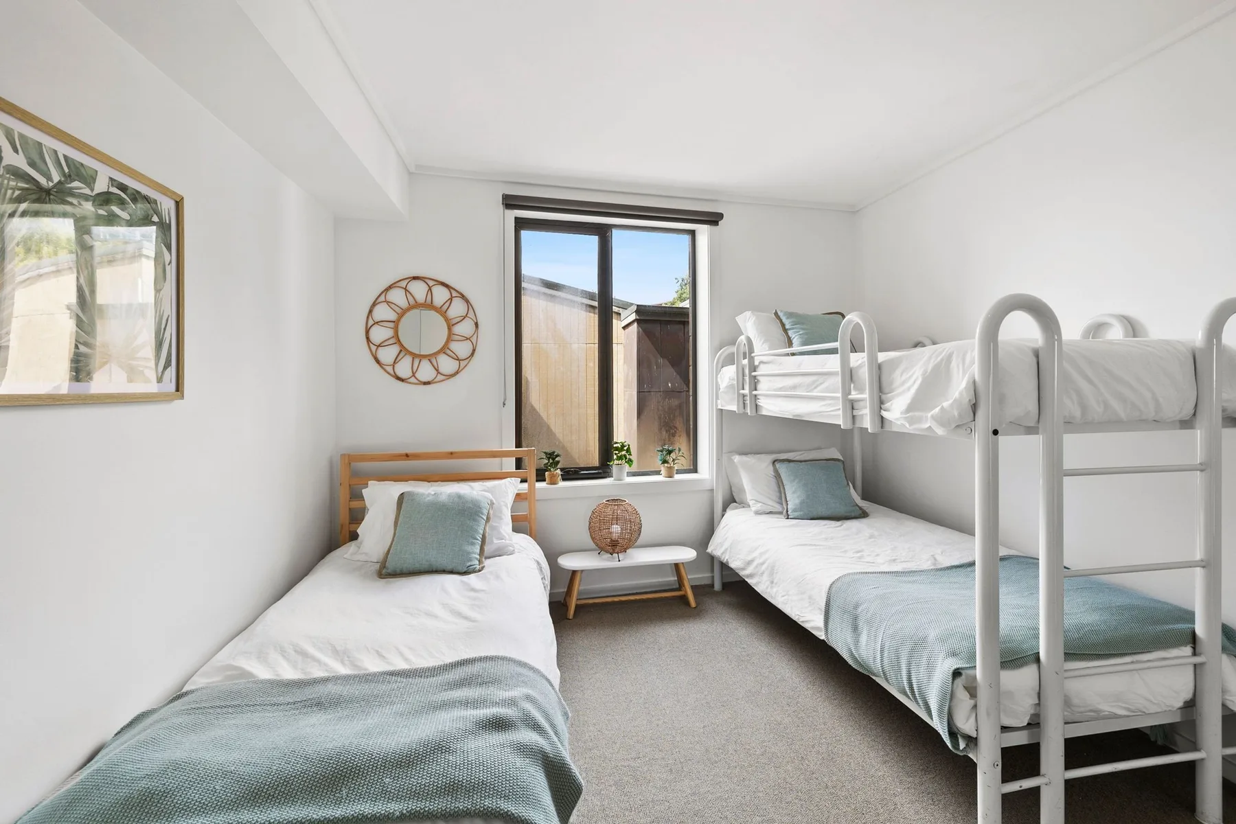 Un dormitorio luminoso con literas, una cama individual y una ventana.