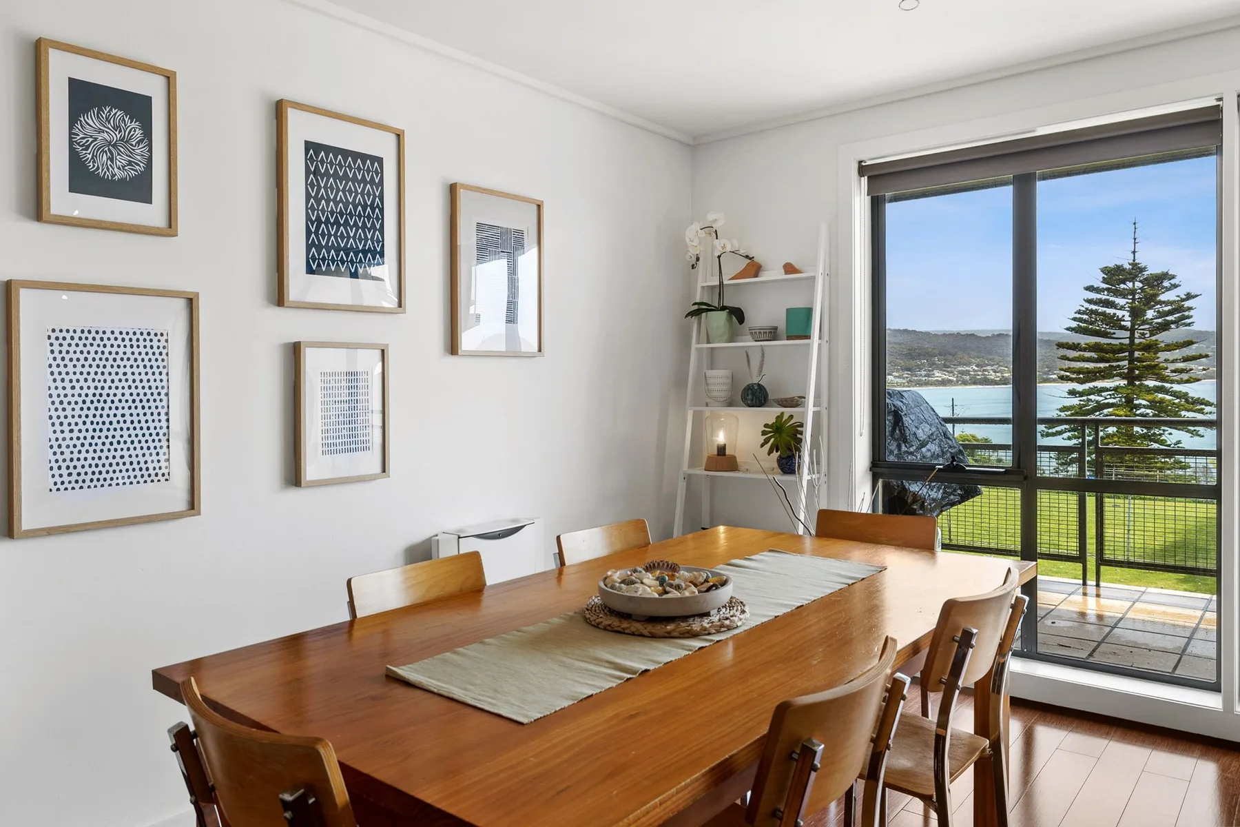 Comedor con una mesa de madera y grandes ventanales con vistas a zonas verdes.