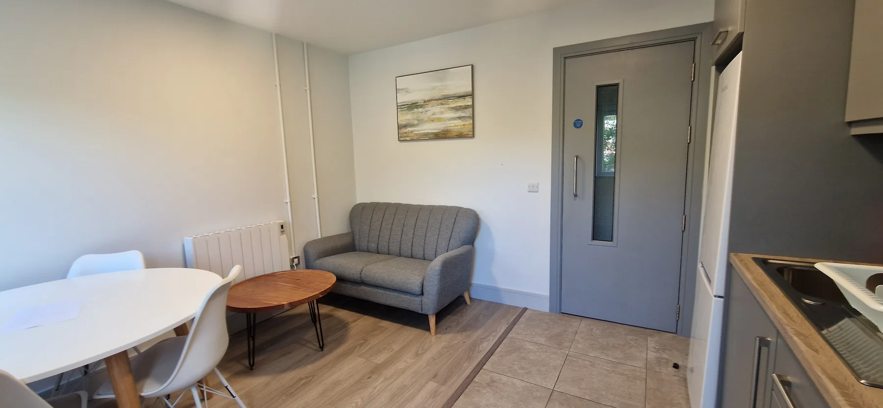 A small dining and sitting area with a table, chairs, and a gray sofa.