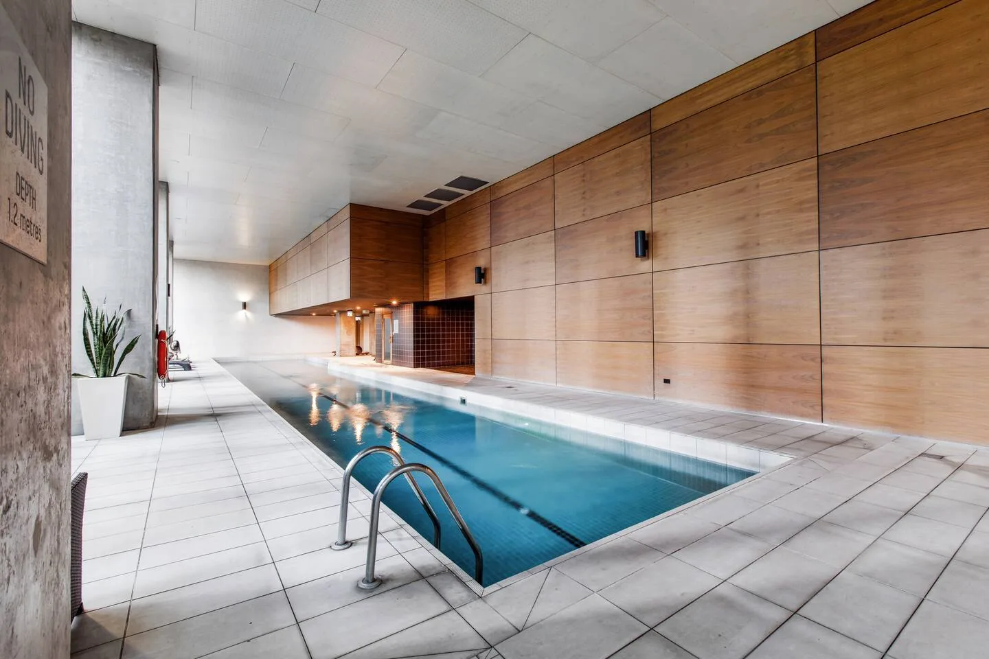 An indoor swimming pool with blue water and tiled flooring.