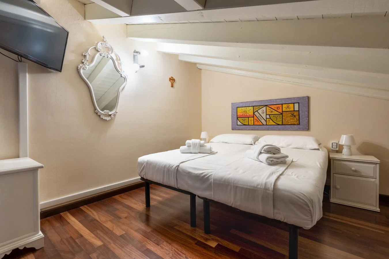A bedroom with a neatly made bed and colorful artwork on the wall.