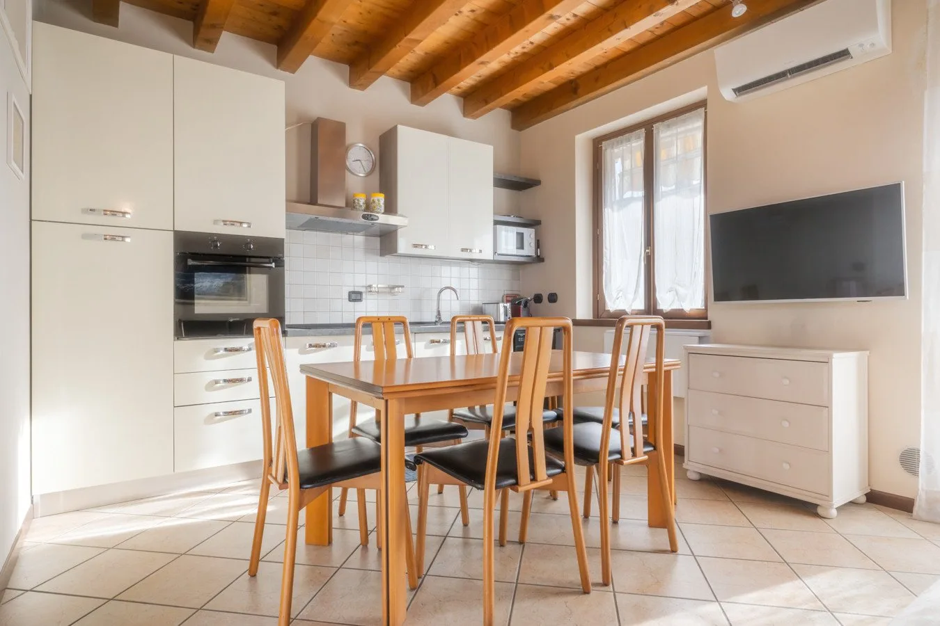 A bright kitchen and dining area with a wooden table and built-in appliances.