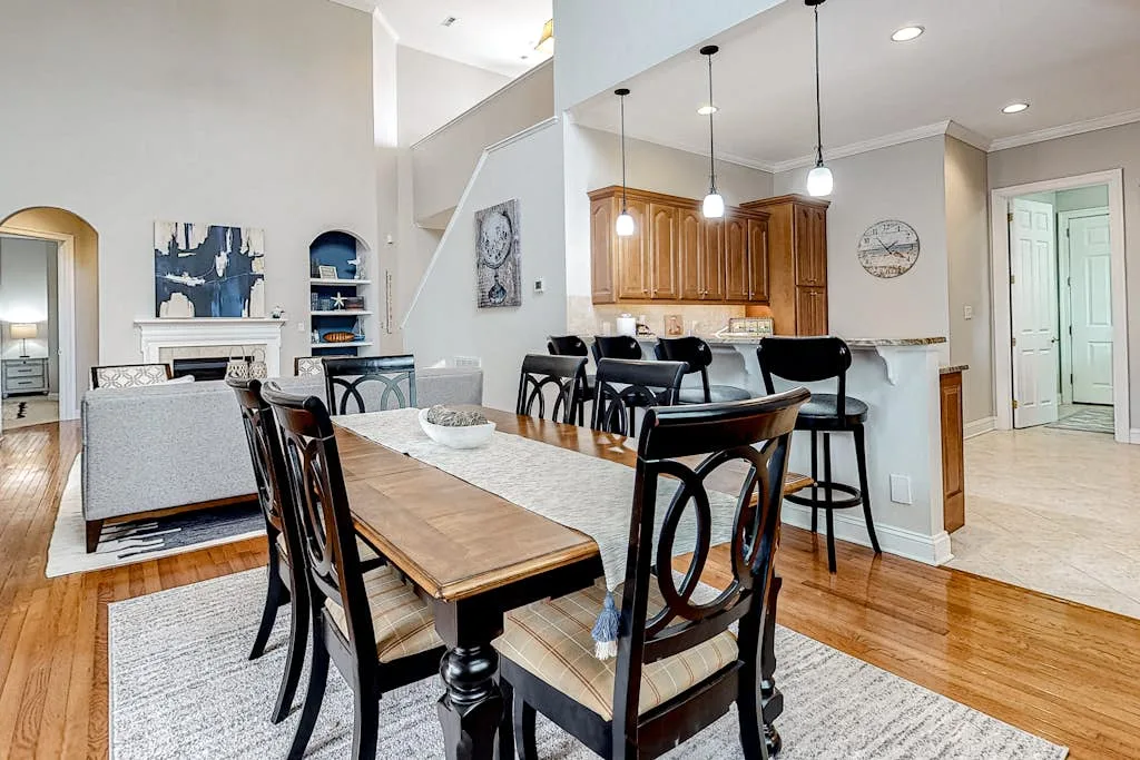 Un espacio abierto de comedor y sala tiene una mesa de madera junto a una isla de cocina.