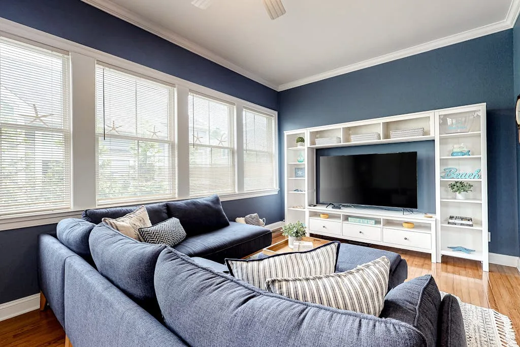 A living room with blue seating arranged in front of a television and shelving.