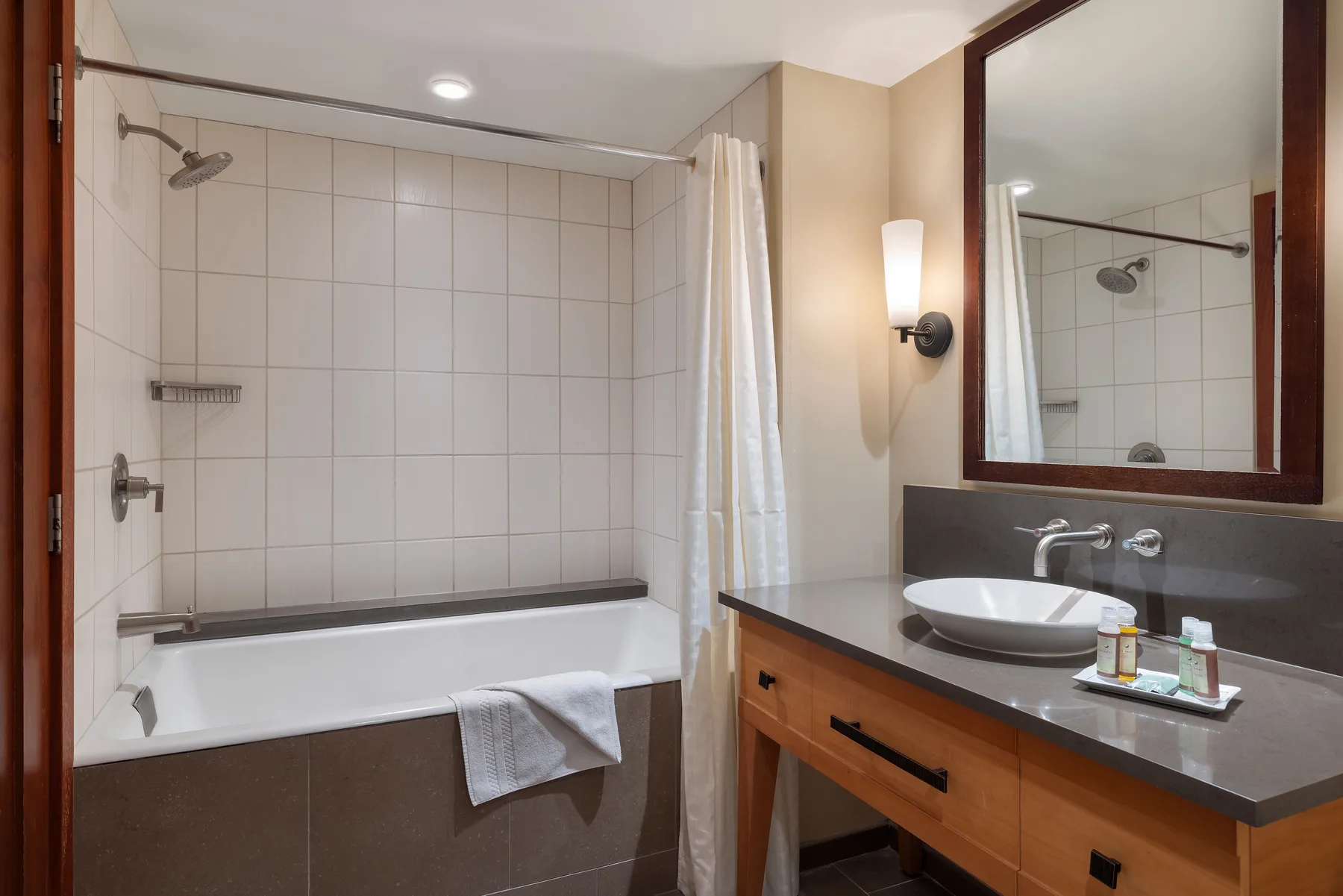Un baño con bañera y ducha junto a un lavabo y un espejo grande.