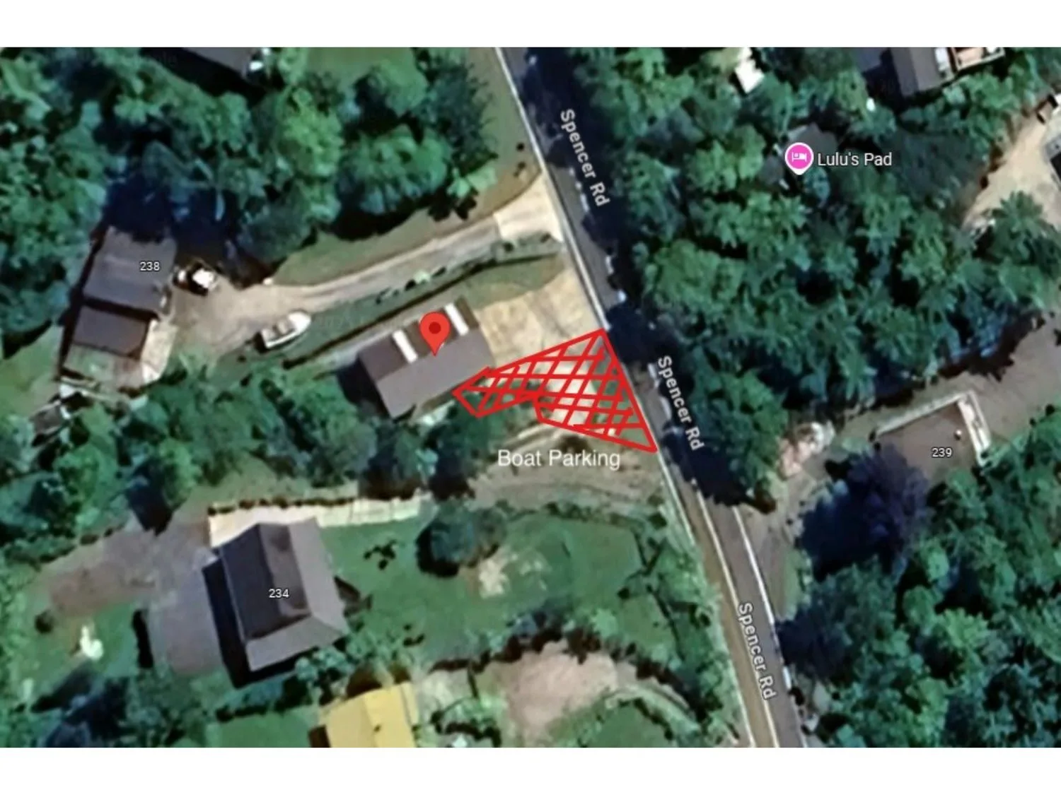 An aerial view shows several buildings surrounded by trees along a road.