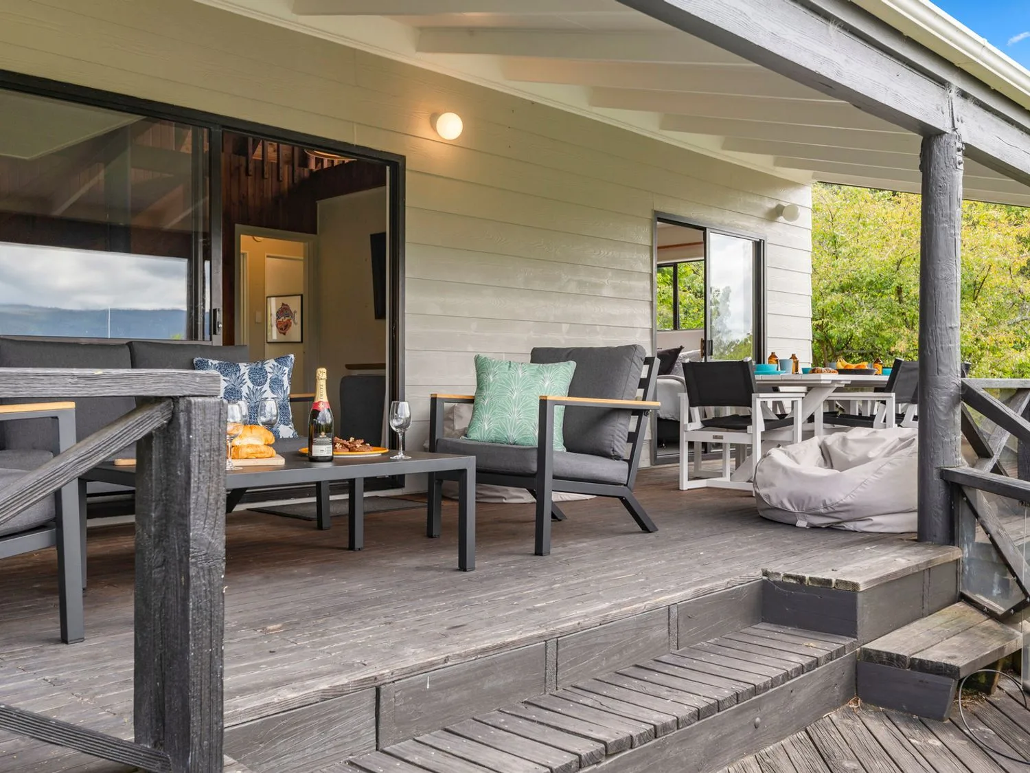 A covered outdoor deck has lounge seating and a dining table.