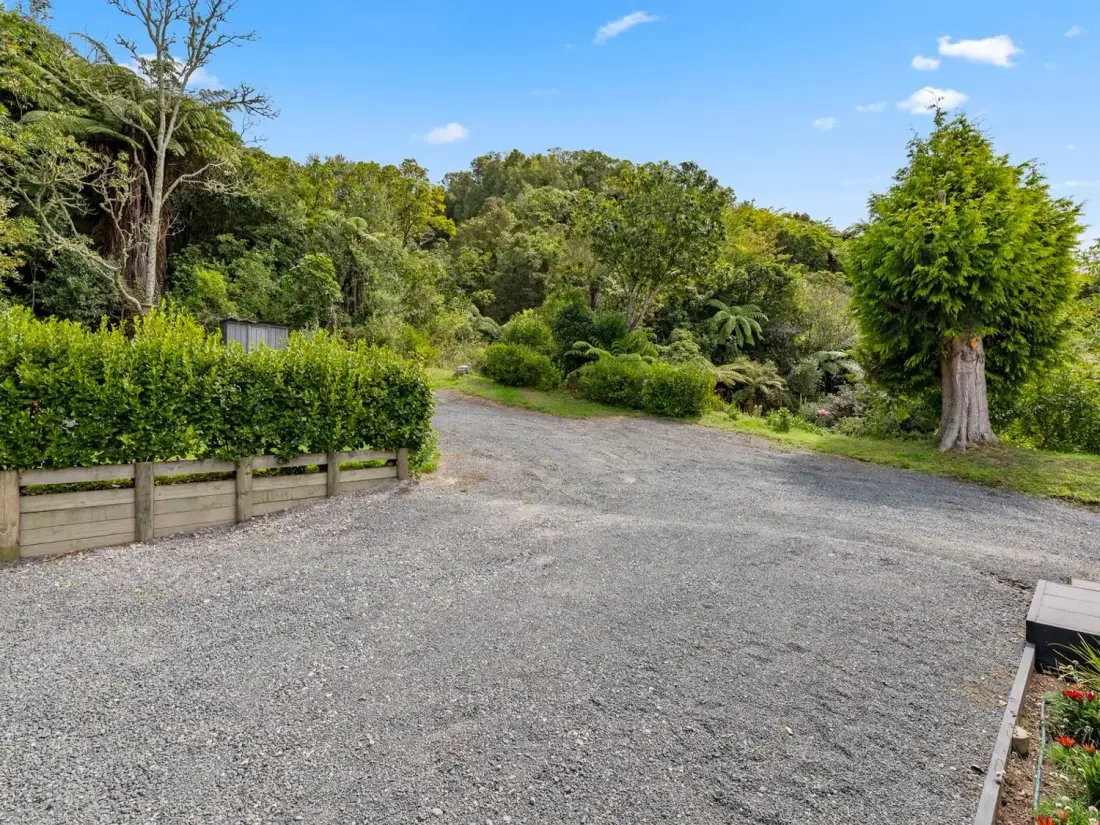 A gravel driveway with trees and bushes surrounding it at Splendour on Spencer - Lake Tarawera Holiday Home in Lake Tarawera
