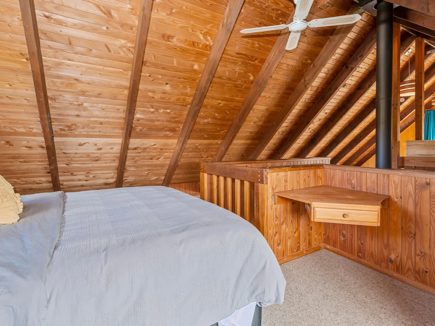 A bedroom with a bed a ceiling fan wooden paneled walls and a small wooden desk attached to the wall at Splendour on Spencer - Lake Tarawera Holiday Home Lake Tarawera