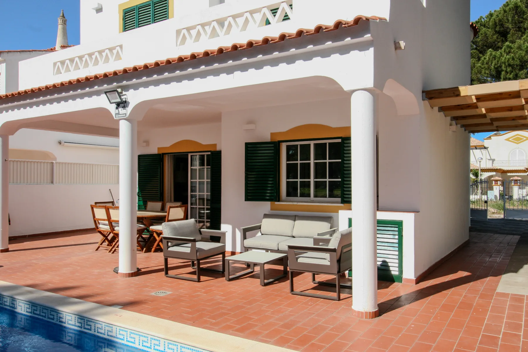 A villa patio with outdoor seating beside a swimming pool.