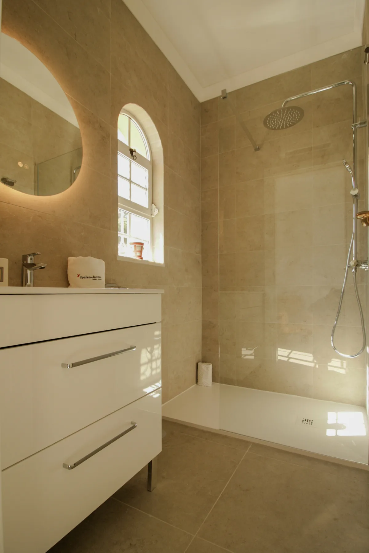 A bright bathroom with a vanity and a walk-in shower.