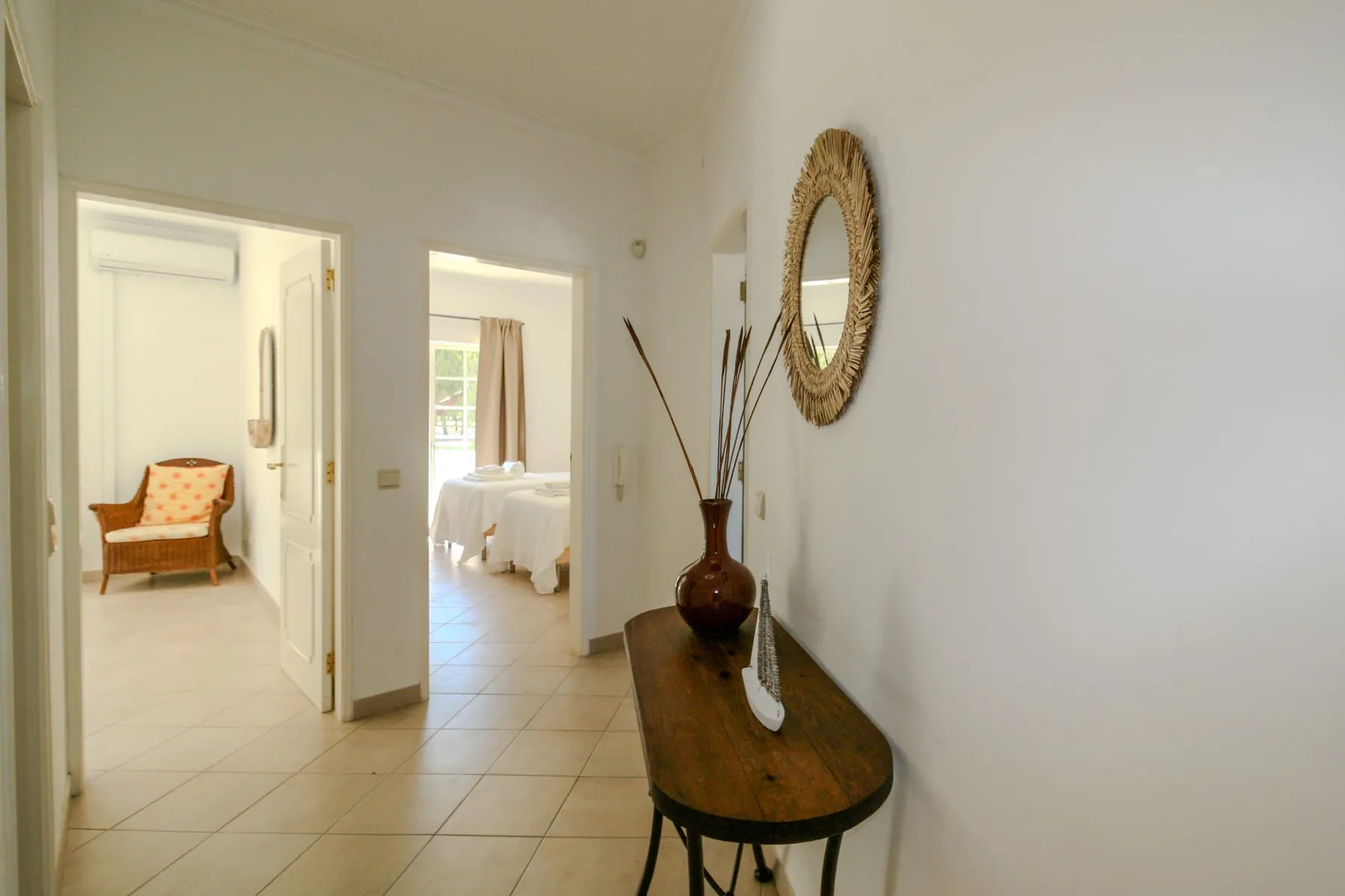 A bright hallway opens toward a bedroom, with a console table along the wall.