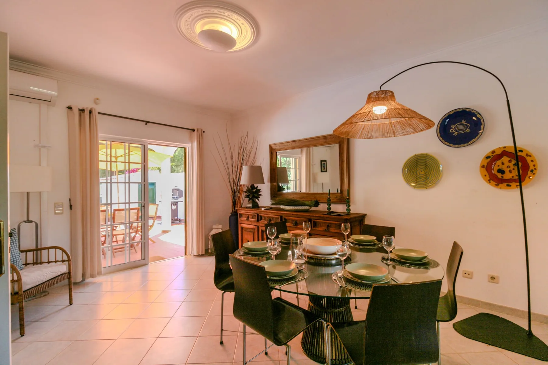 A dining area with a set table and sliding glass doors opening onto a patio.