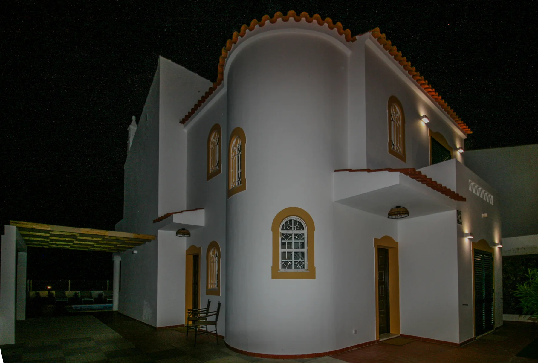 A white two-story villa with arched windows is shown at night.