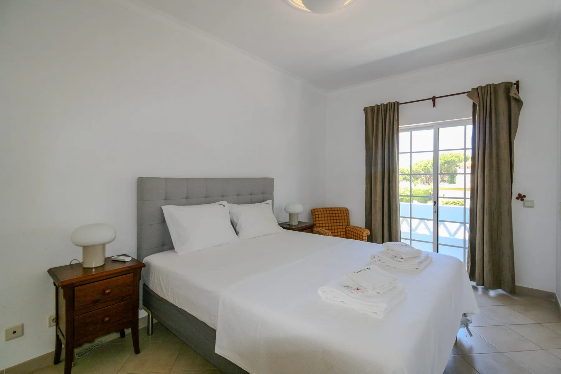 A bright bedroom with a double bed and glass doors opening onto a balcony.
