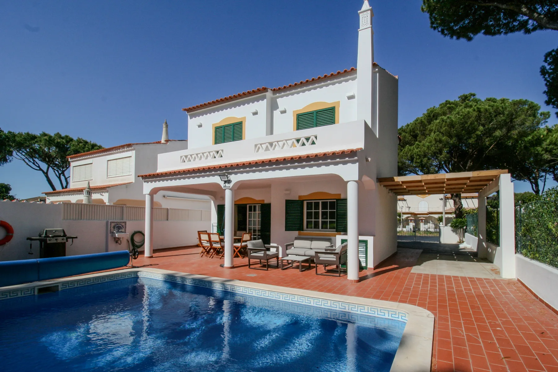 A white villa with a swimming pool and a covered patio.