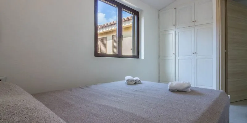 Un dormitorio con una cama, armarios empotrados y una ventana.
