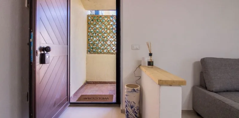 Entrada con una puerta de madera abierta, una encimera estrecha y asientos grises.