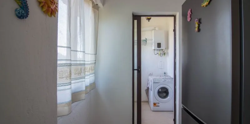 Un pasillo estrecho da a una zona de lavado con una lavadora.