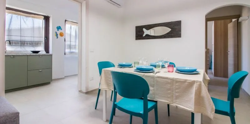 Un comedor con la mesa puesta y asientos de color azul brillante.