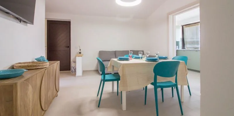 Un comedor con una mesa puesta con vajilla y sillas verde azulado.