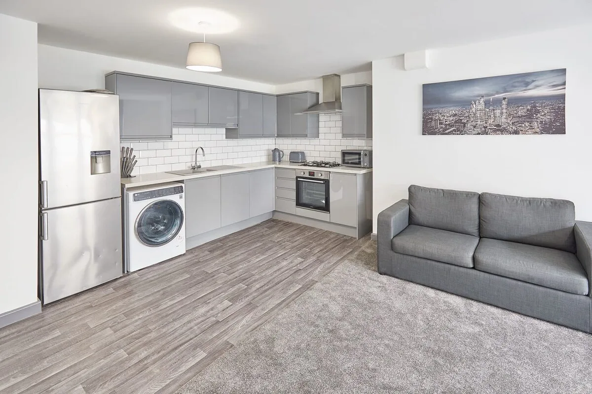 A compact kitchen and living area with gray seating and modern appliances.