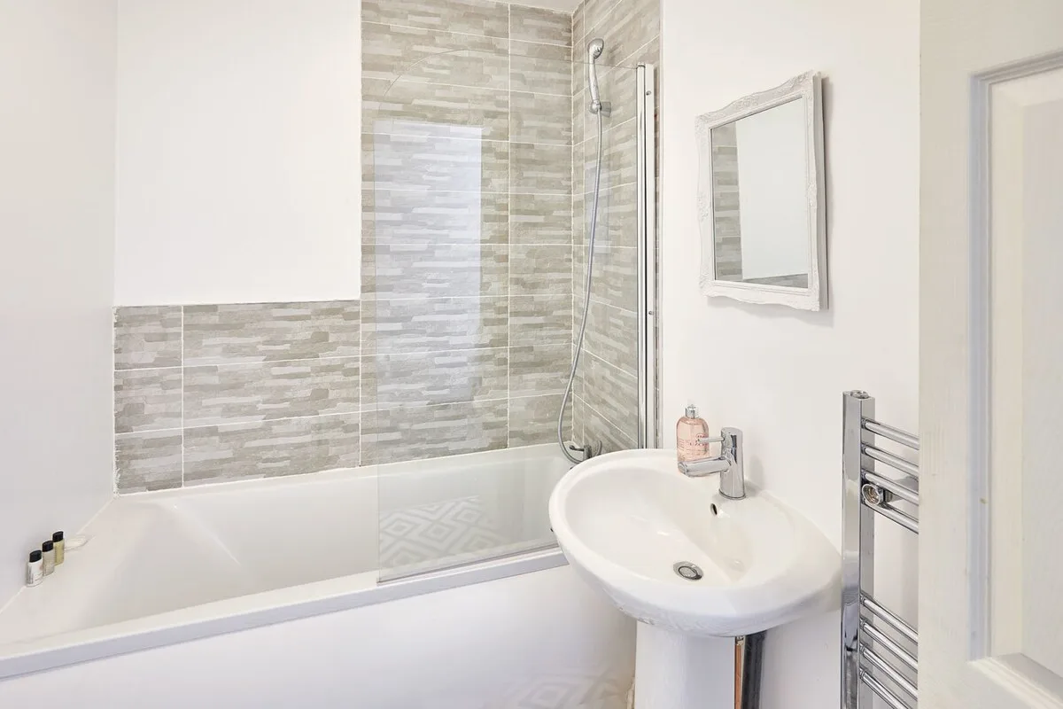 A bright bathroom with a bathtub, shower, and pedestal sink.