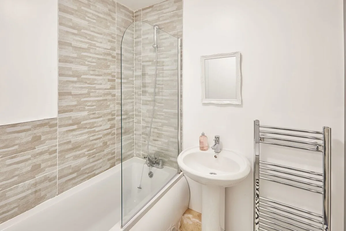 A bathroom with a glass shower screen and a pedestal sink.
