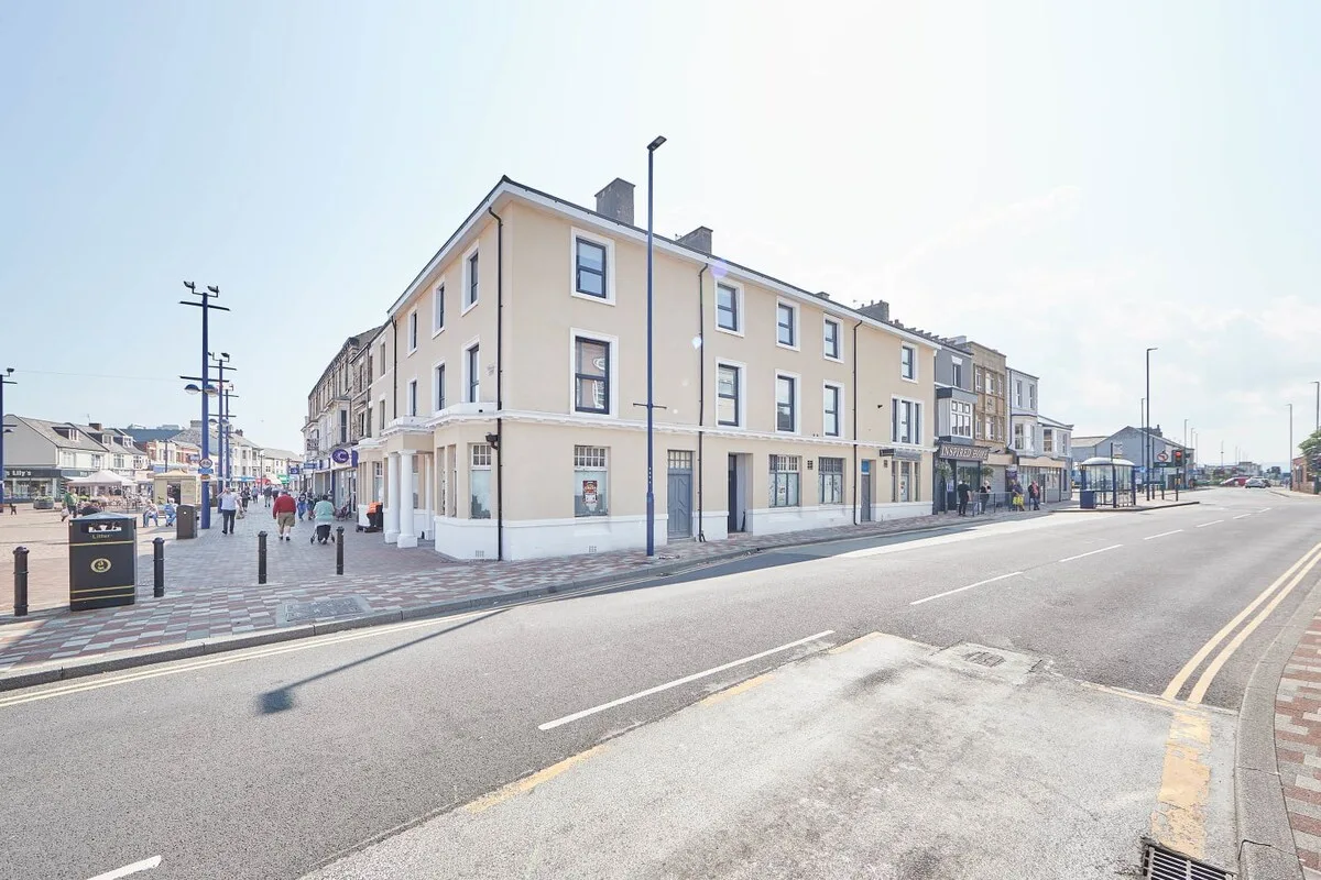 A row of multi-story buildings stands along a broad street.
