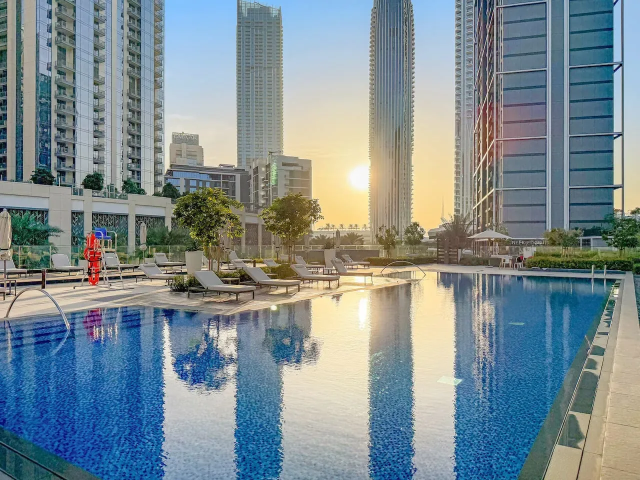 Una piscina al aire libre refleja los edificios altos circundantes al atardecer.