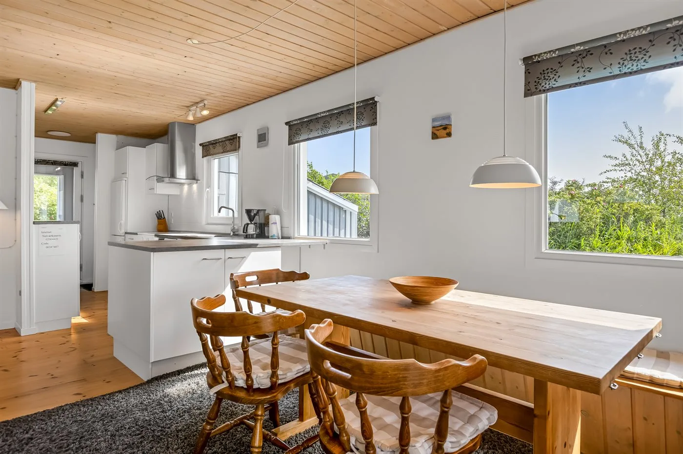 Comedor integrado con cocina y una mesa de madera bajo lámparas colgantes.