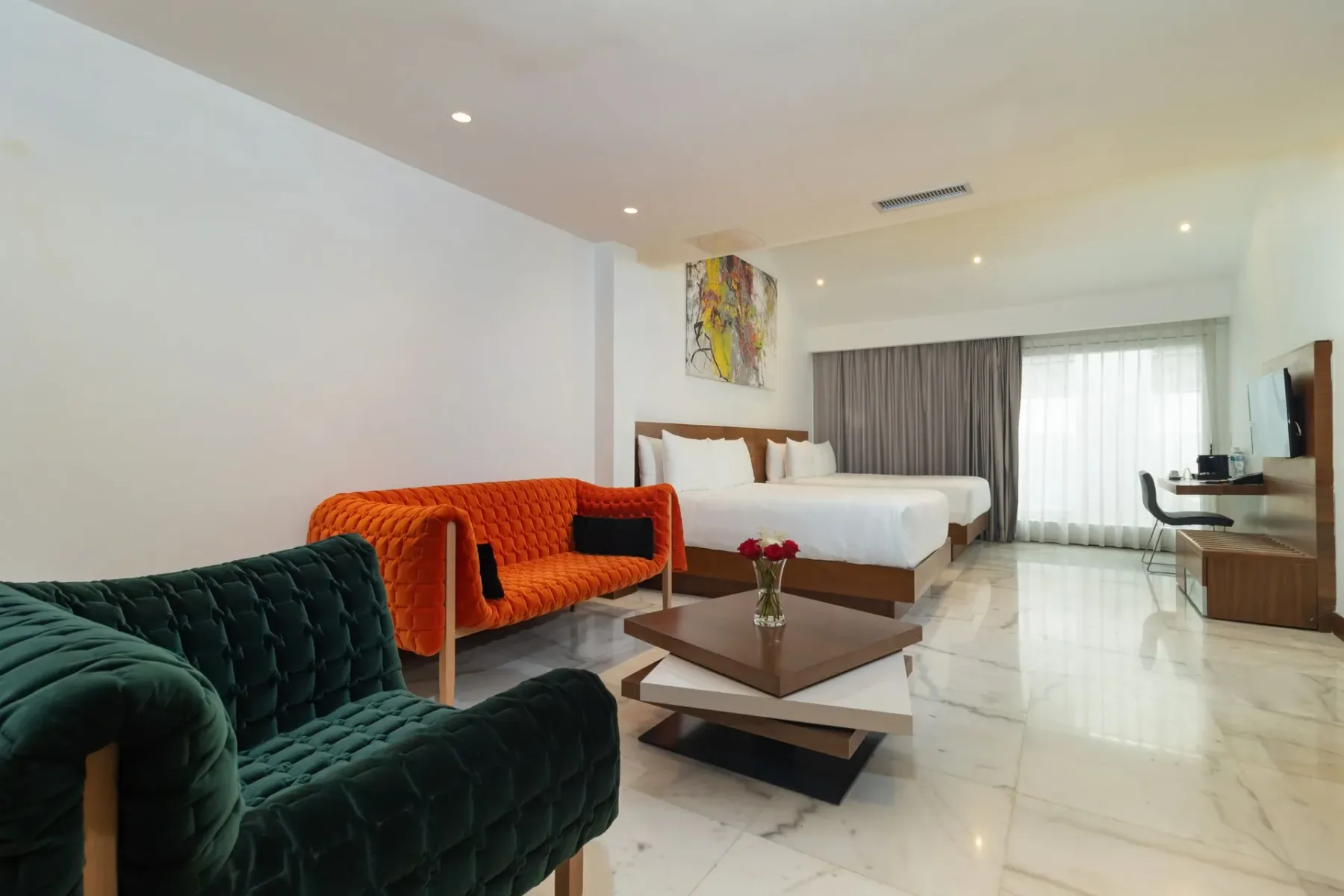 Habitación de hotel con zona de estar, dos camas y una mesa de centro.