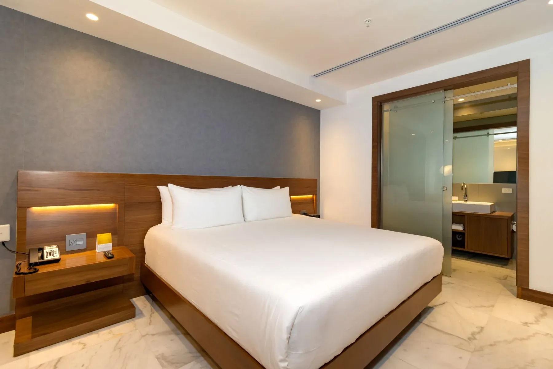 Dormitorio de hotel con una cama y una puerta de cristal en el baño.
