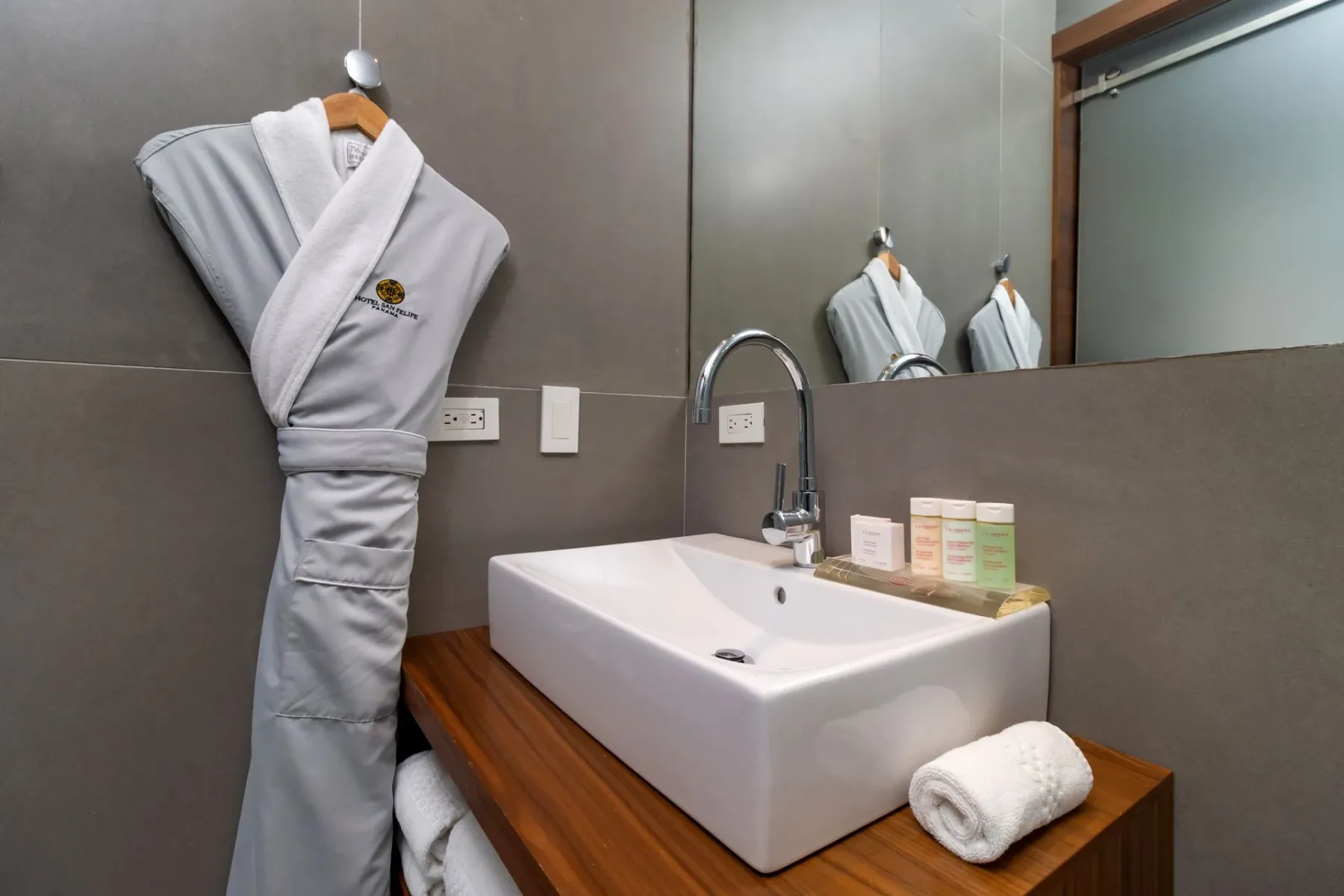 Baño con un lavabo blanco sobre una encimera de madera y un espejo.