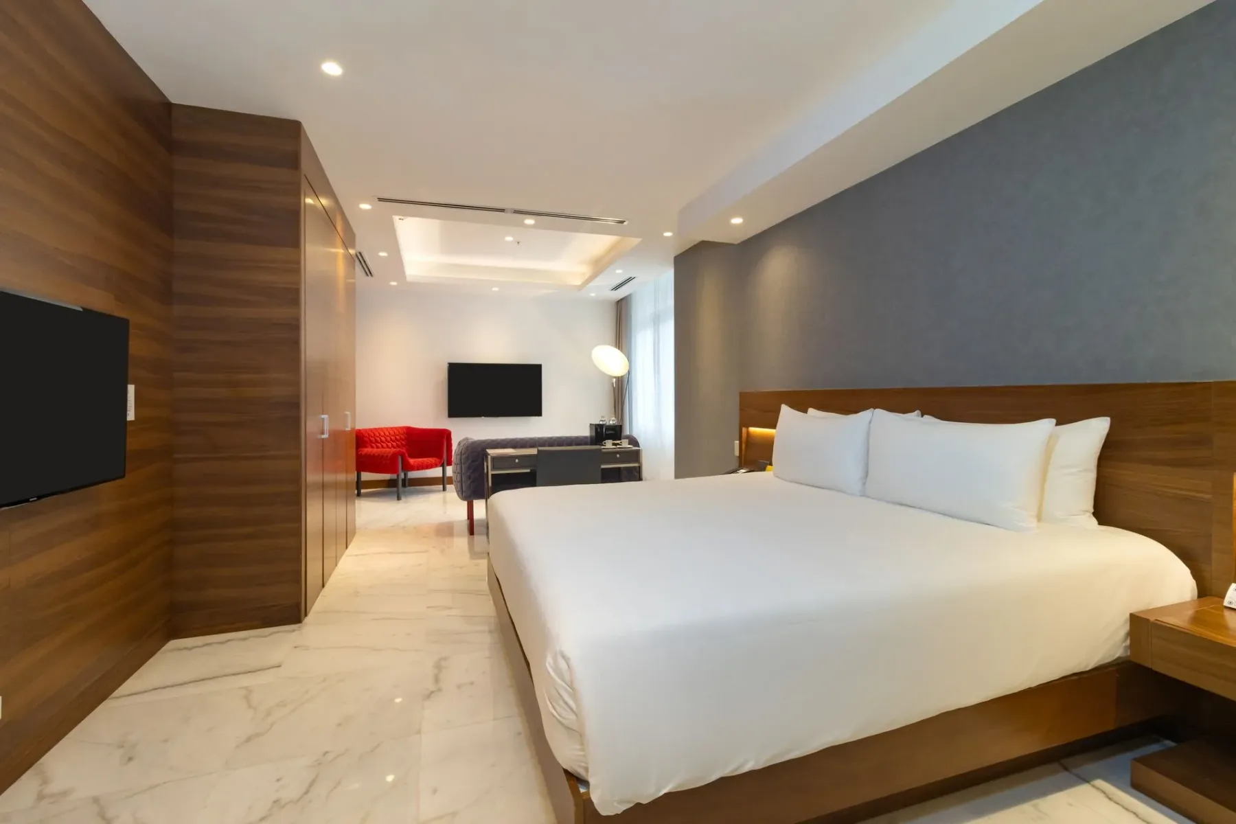 Dormitorio de hotel con una cama grande, un televisor y una zona de estar.