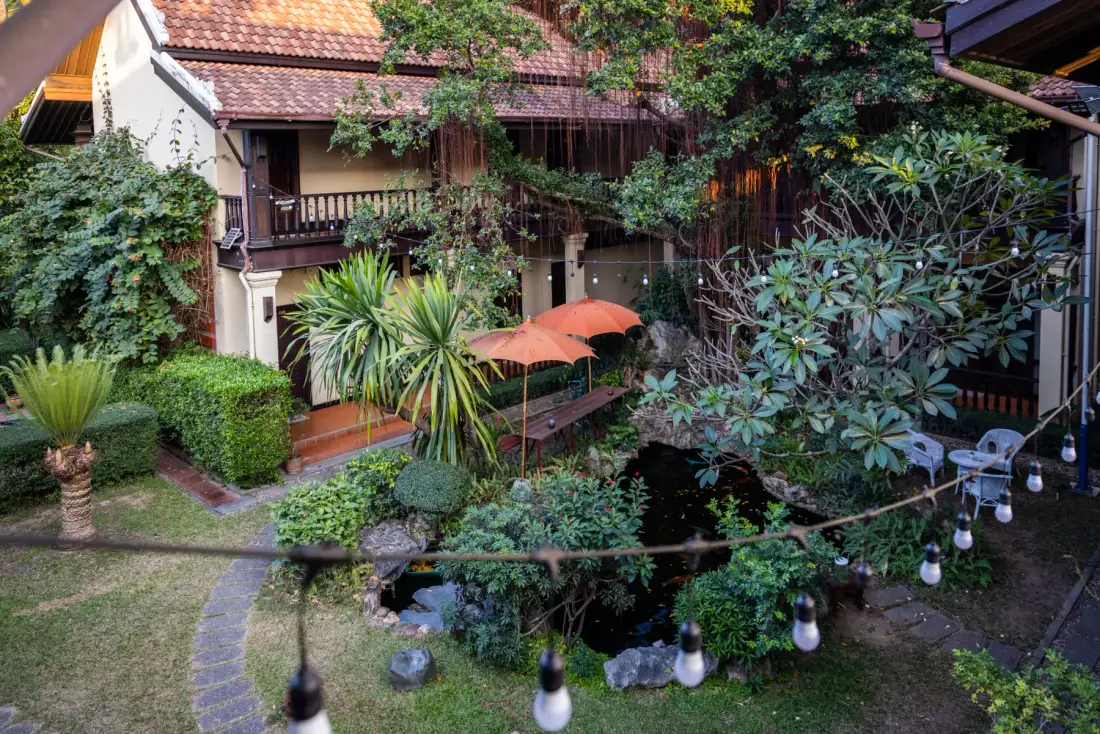 Césped y jardín del hotel vistos desde un balcón superior, con sombrillas y arbustos podados.