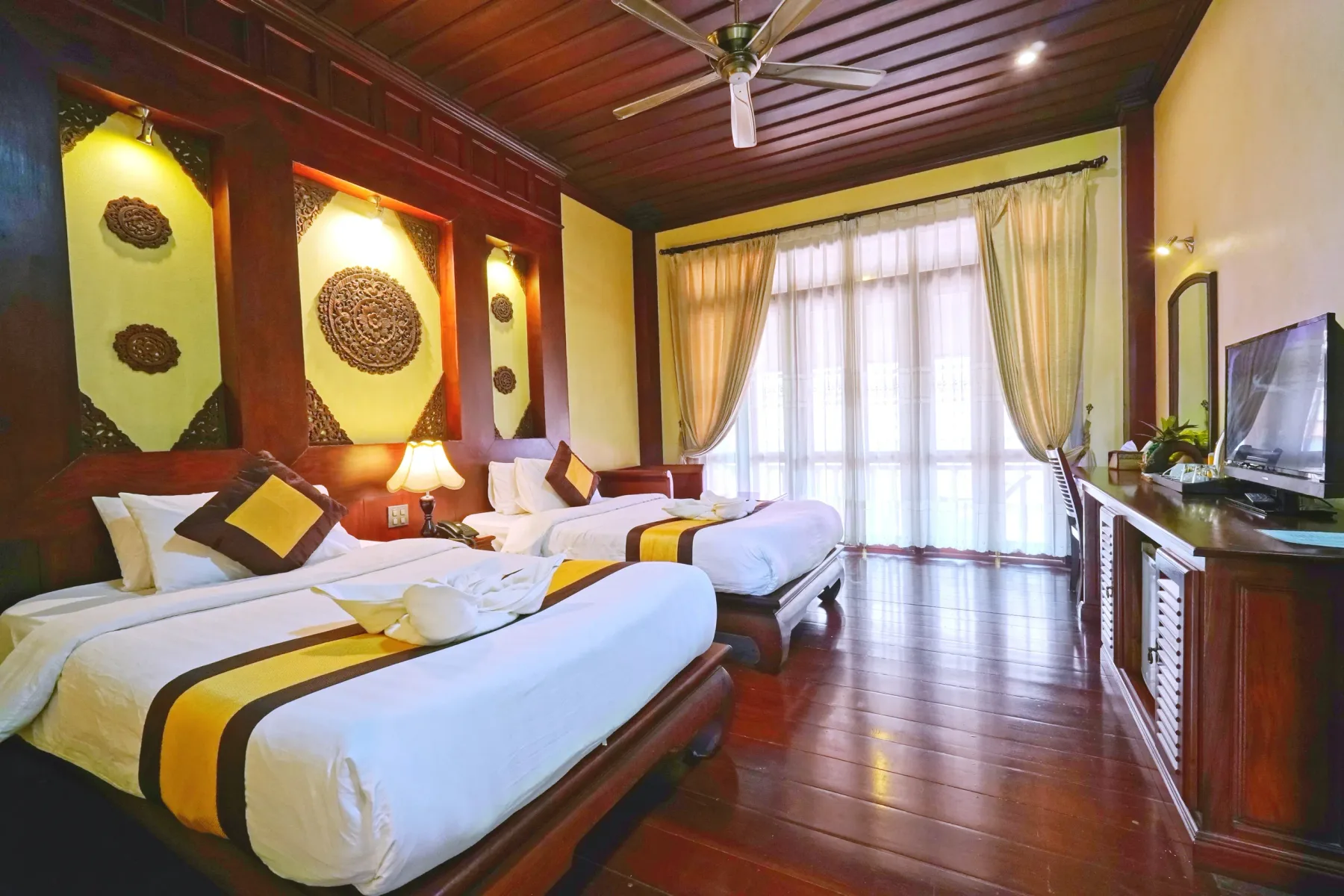 Dos camas individuales junto a las puertas del balcón de una habitación Deluxe.