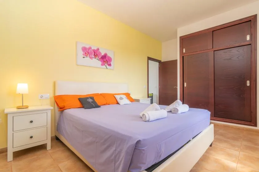 Un dormitorio con una cama, una mesita de noche y un armario de madera oscura.