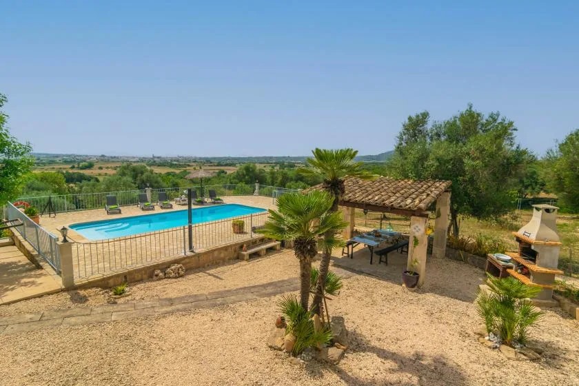 Una zona de piscina al aire libre con una estructura techada de tejas y árboles alrededor.